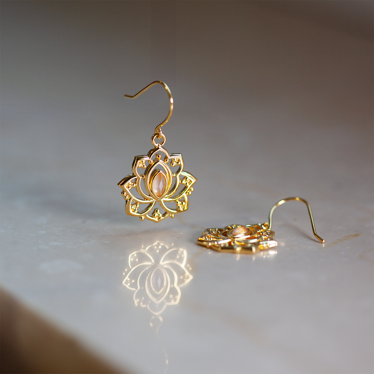 Goldene hängende Ohrringe mit einem rosa Stein