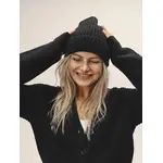 Weibliches Model, welches eine schwarze Mütze trägt und sich an den Kopf fasst