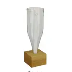 Eine umgedrehte transparente Glasflasche mit offenen Boden, mit brennender Kerze darin auf einem Holzsockel