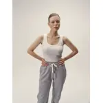 Weibliches Model mit weißem Rundhals-Top und hellgrauer Jogginghose