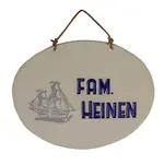 Weißes ovales Tonschild mit blauer Aufschrift "Heimathafen" mit Schiffsymbol