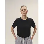 Weibliches Model mit Blick in die Kamera, Fokus auf das schwarze Rundhals-T-Shirt