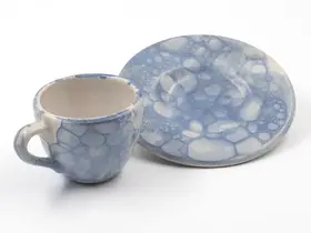 Komplettes Set mit blau-weiß glasierter Tasse und Untertasse mit weißem Hintergrund