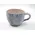 Keramiktasse mit Henkel in Blau- und Weißtönen mit marmorierter Oberfläche steht auf einer hellen Fläche vor neutralem Hintergrund.