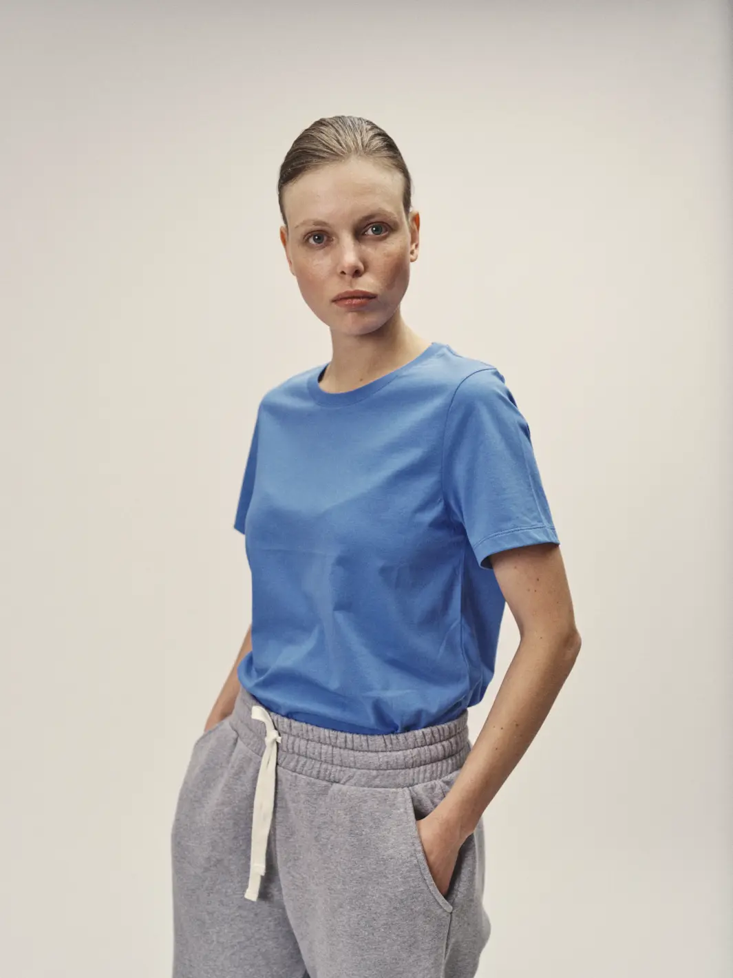 Weibliches Model mit Blick in die Kamera, mit Fokus auf dem blauen Rundhals-T-Shirt